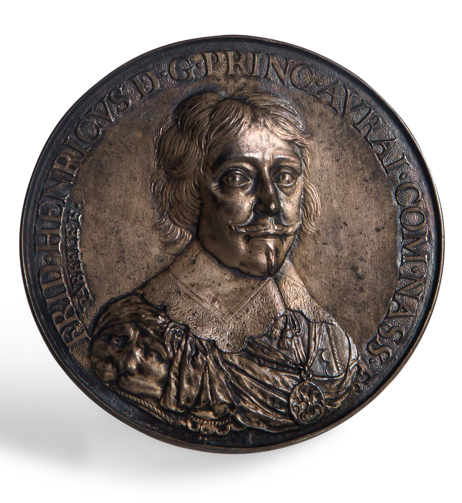 Zilveren penning met op de voorzijde het borstbeeld van prins Frederik Hendrik, en face naar rechts. De prins draagt het pendant van de Orde van de Kousenband om zijn hals. Rondom het portret staat de tekst: "FRID.HENRICVS D.G.PRINC.AVRAI.COM. NASS.EC". 
